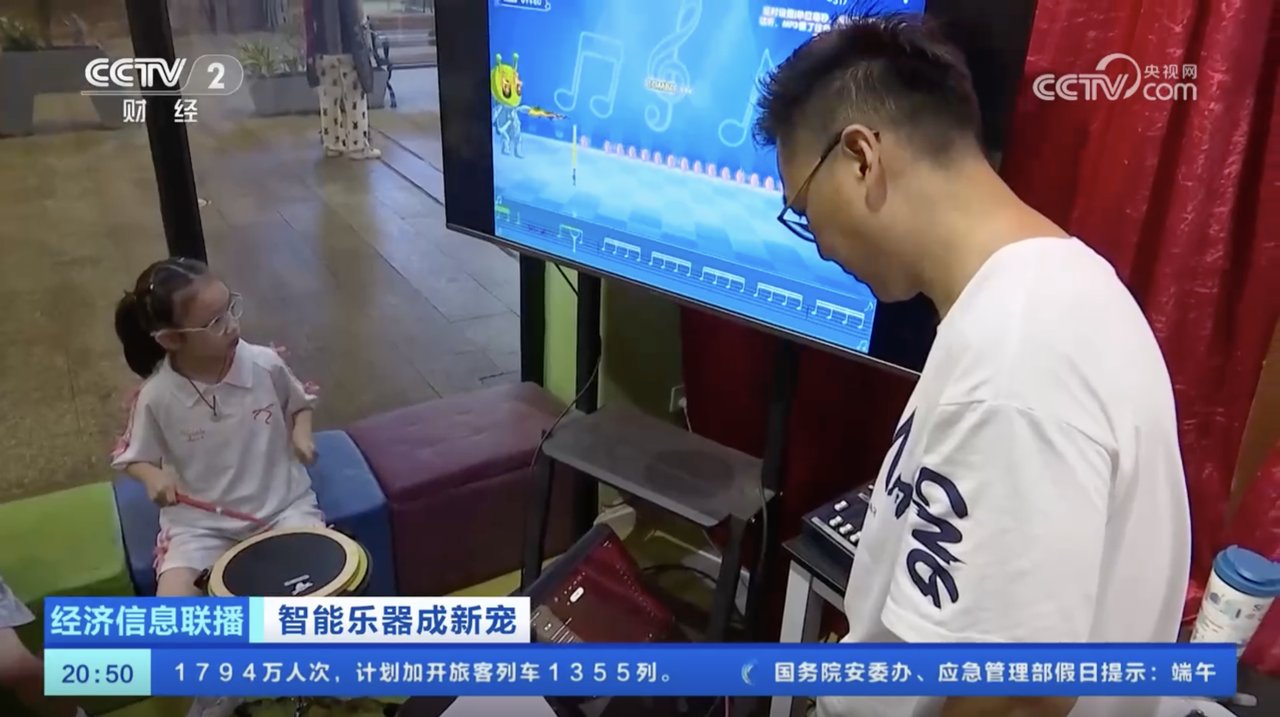 央视记者镜头下，家长陪同小女孩在琴行用电视端的诺艾智能打击板练习
